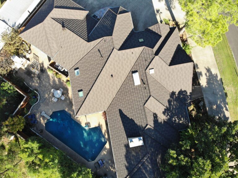 Aerial view of a house with a stone-coated steel roof, a swimming pool, and a patio area.