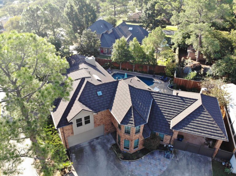 Aerial view of a two-story brick house with a stone-coated steel roof, a backyard swimming pool, and a driveway.